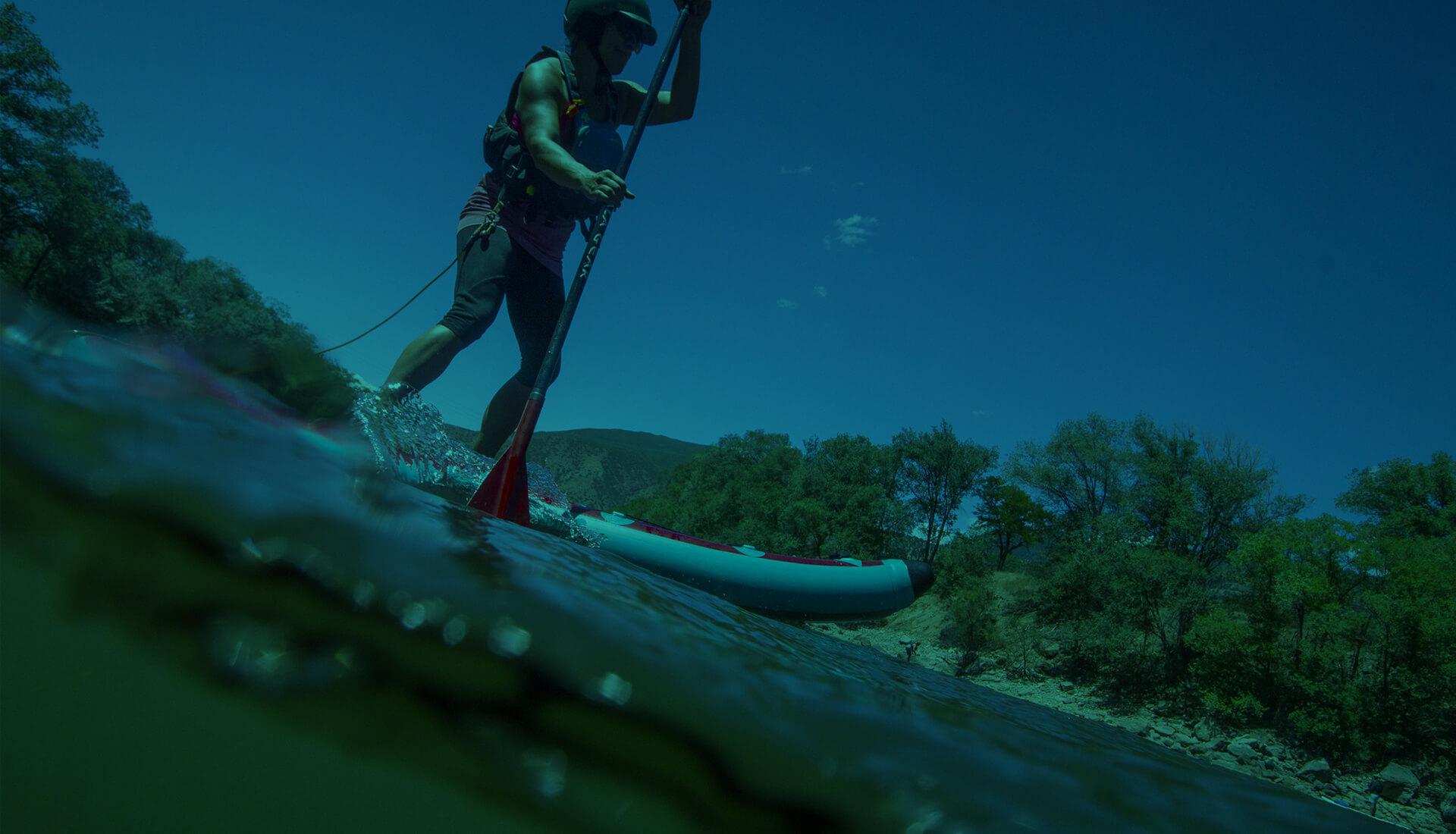 Woman stand-up paddleboarding on river.